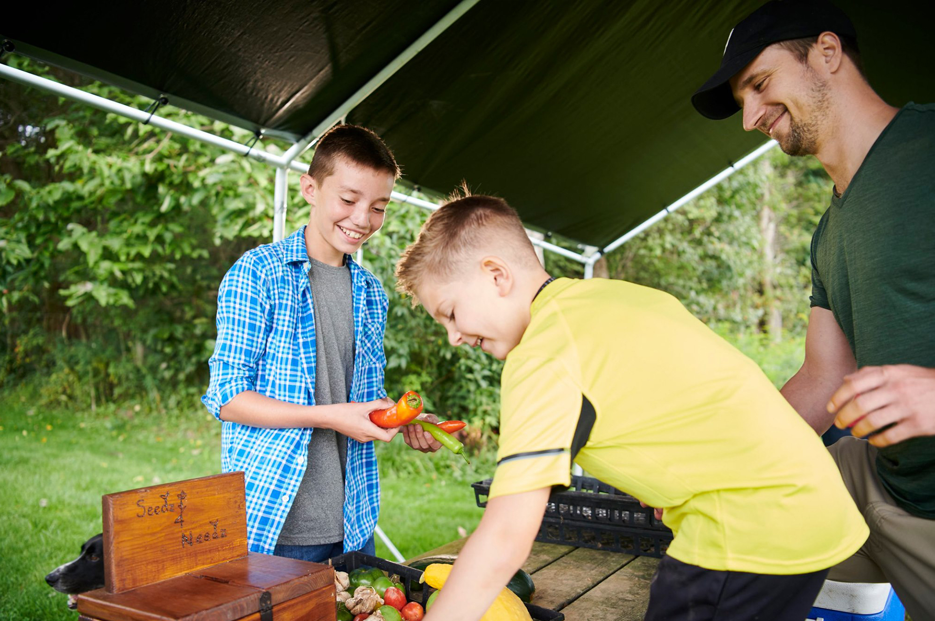 Jakob selling vegetables to a young boy and his dad